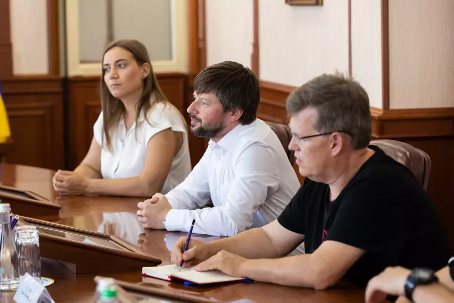 Два чоловіки і жінка - представники Червоного Хреста сидять за столом на переговорах з керівниками НГУ