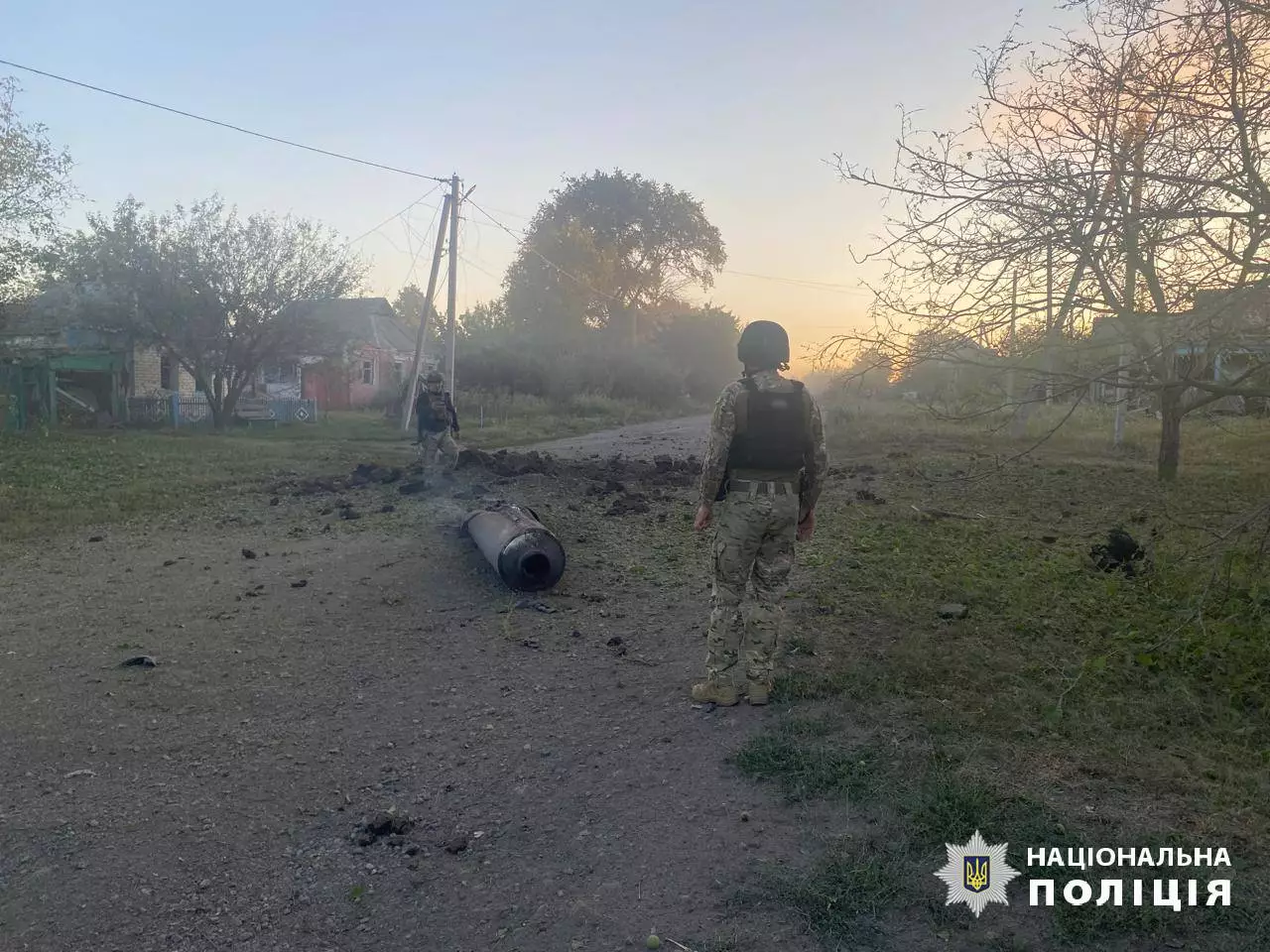 Двоє військових розглядають частину ракети на вулиці села