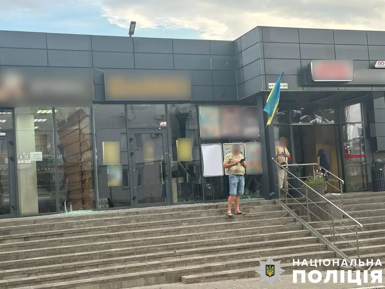 Чоловіки стоять біля магазину, в якому розбиті вітрини та вікна