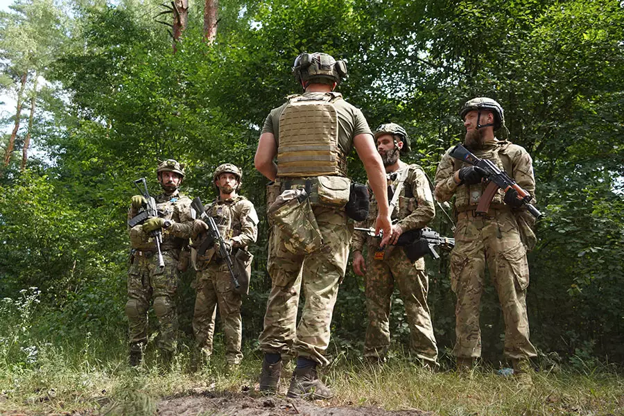 Інструктор, який стоїть спиною, розповідає військовим, які тримають в руках автомати