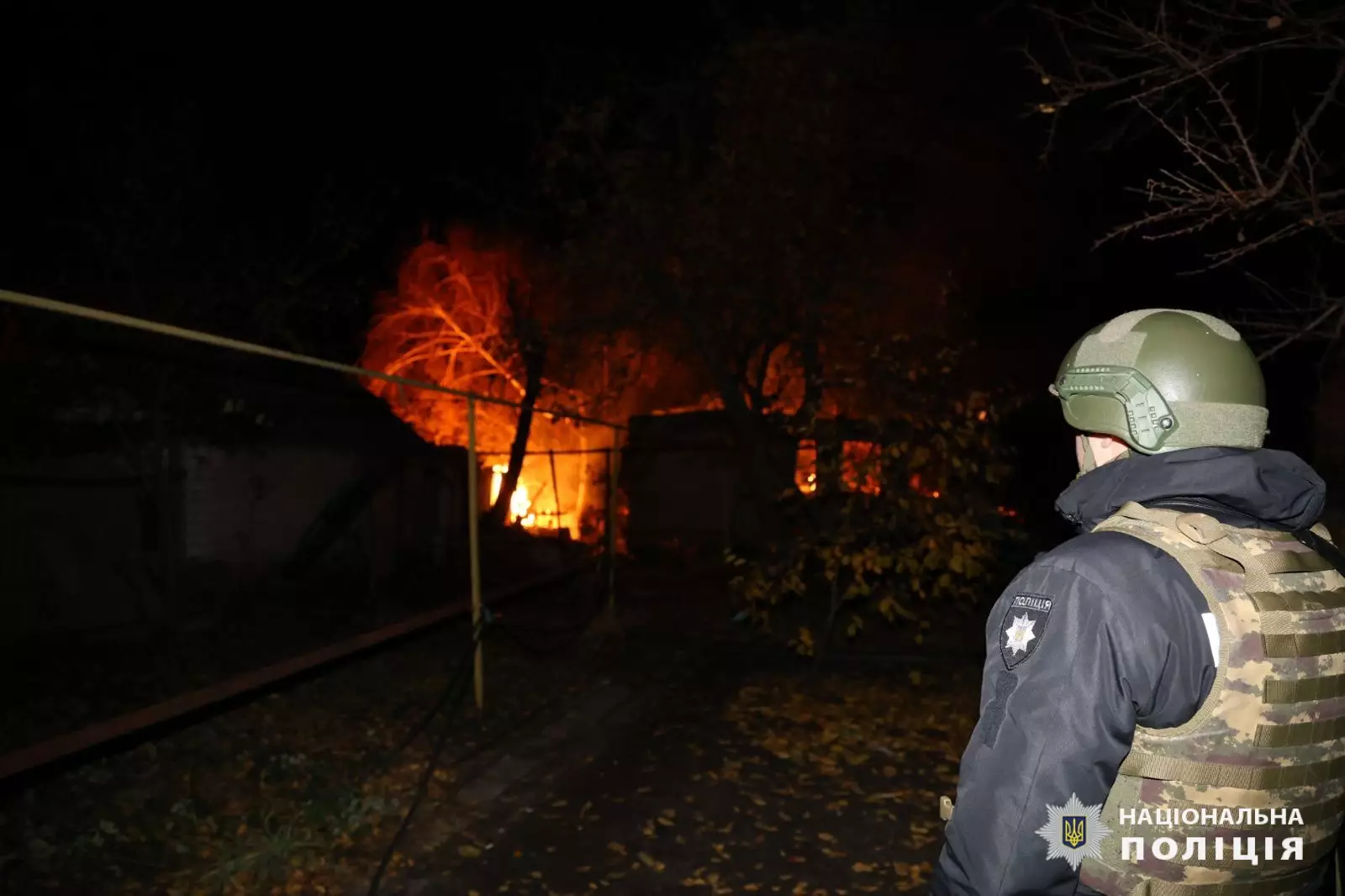 Поліцейський оглядає подвір'я палаючого будинку