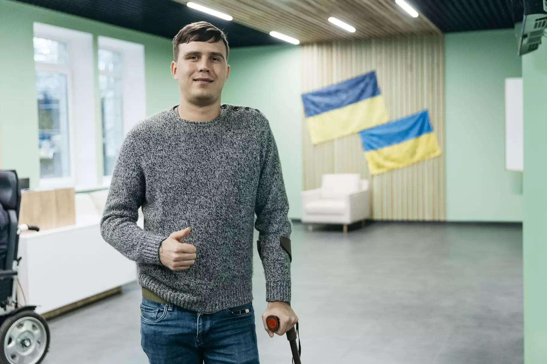 Усміхнений Касік стоїть, спираючись на паличку,в холі госпіталя