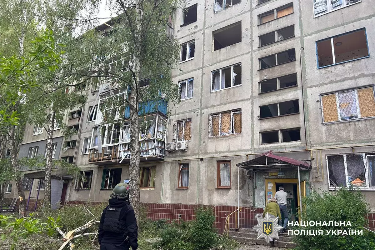поліцейський оглядає пошкоджену багатоповерхівку